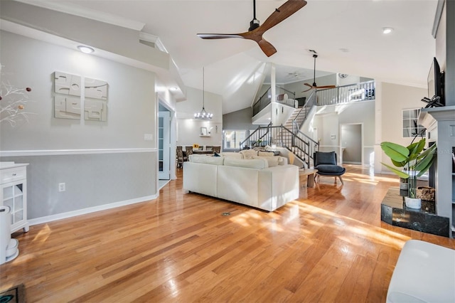 living room with ceiling fan, vaulted ceiling, and light wood-type flooring