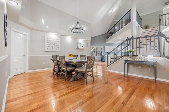 dining space featuring light hardwood / wood-style flooring, high vaulted ceiling, and a notable chandelier