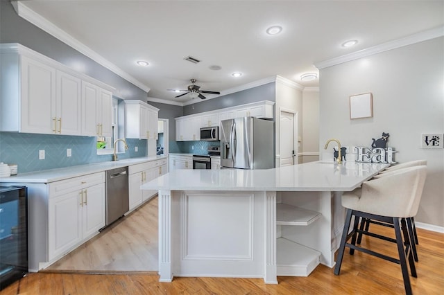 kitchen with white cabinets, appliances with stainless steel finishes, ceiling fan, and beverage cooler