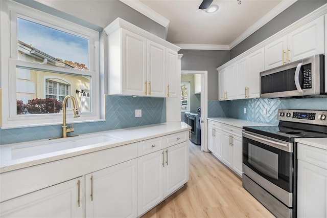 kitchen featuring backsplash, crown molding, sink, white cabinetry, and stainless steel appliances