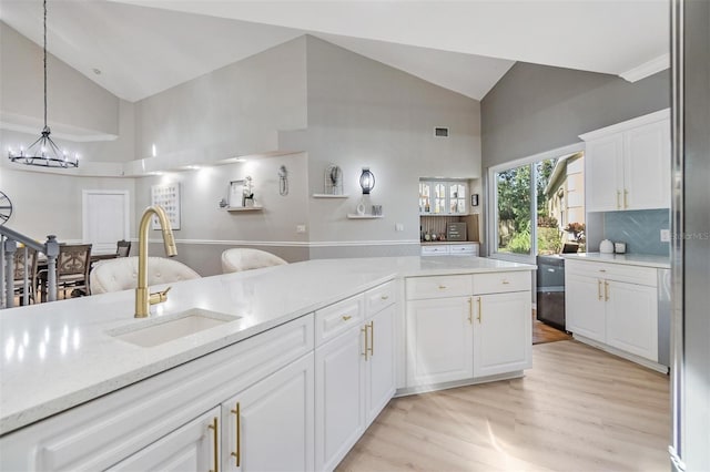 kitchen featuring backsplash, sink, a chandelier, white cabinetry, and hanging light fixtures