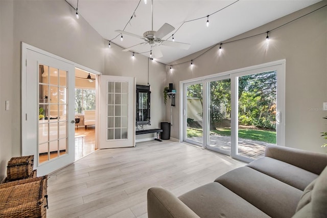 living room featuring ceiling fan, french doors, a high ceiling, and light wood-type flooring