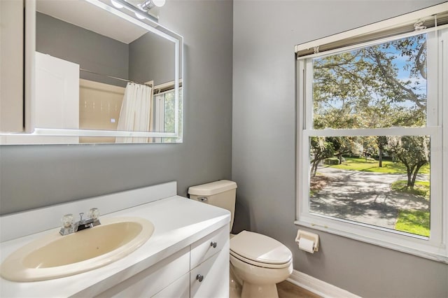 bathroom with walk in shower, vanity, toilet, and plenty of natural light