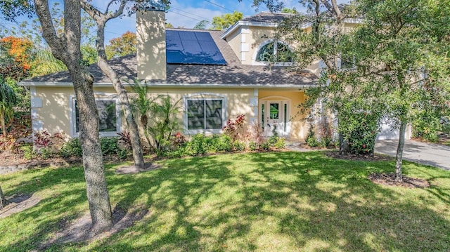 view of front of property featuring solar panels and a front lawn