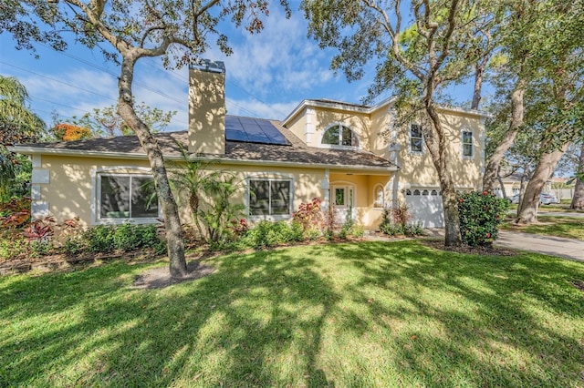 view of front facade with solar panels, a garage, and a front lawn