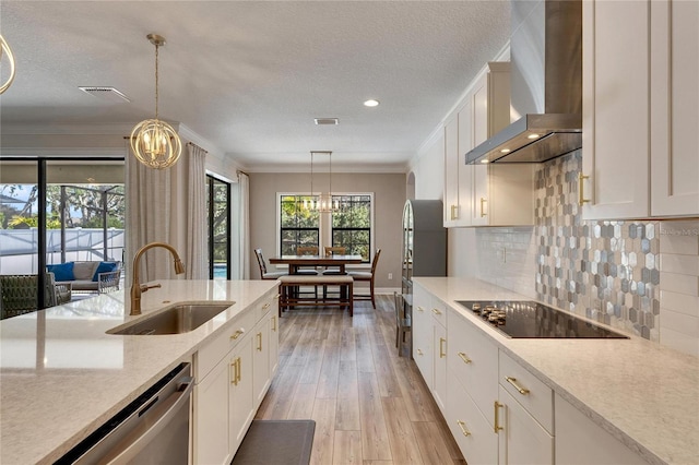 kitchen with wall chimney exhaust hood, dishwasher, sink, and decorative light fixtures