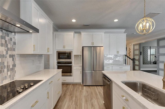 kitchen featuring pendant lighting, white cabinets, wall chimney range hood, decorative backsplash, and appliances with stainless steel finishes