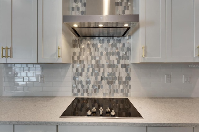 kitchen featuring decorative backsplash, black electric stovetop, white cabinets, and wall chimney range hood