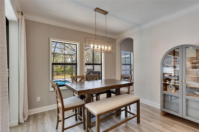 dining area with an inviting chandelier, ornamental molding, a textured ceiling, and light wood-type flooring