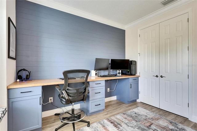 office with built in desk, crown molding, and light hardwood / wood-style flooring