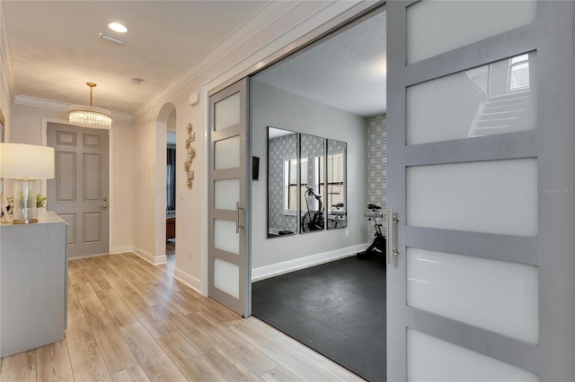 foyer with a notable chandelier, light hardwood / wood-style floors, and ornamental molding