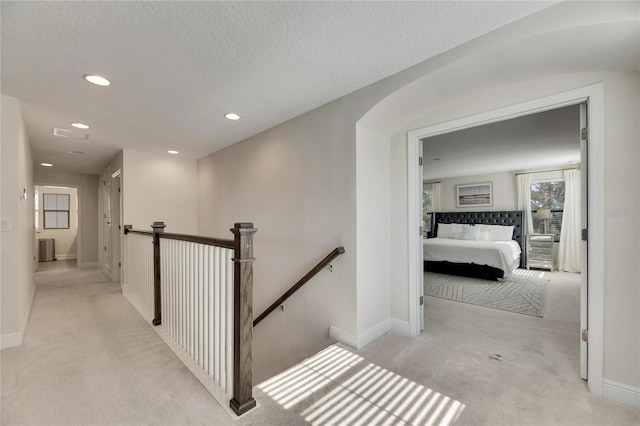 corridor featuring a textured ceiling and light colored carpet