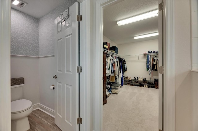 bathroom featuring hardwood / wood-style floors, a textured ceiling, and toilet