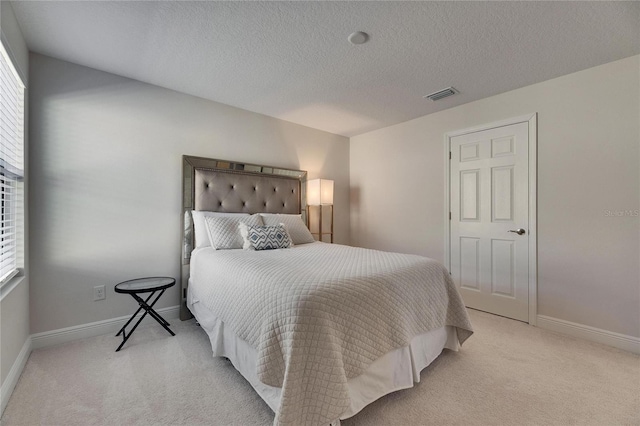 bedroom with light colored carpet and a textured ceiling