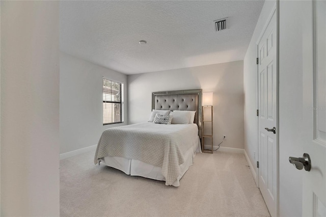 bedroom with light carpet and a textured ceiling