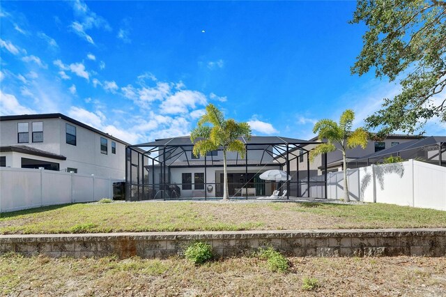 rear view of house featuring a lanai and a lawn