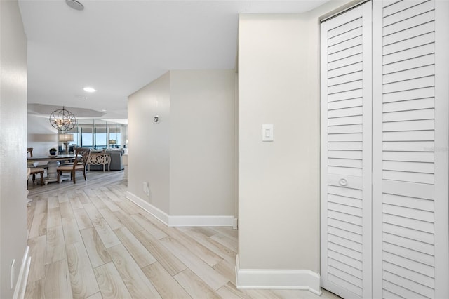 corridor featuring a notable chandelier and light hardwood / wood-style floors