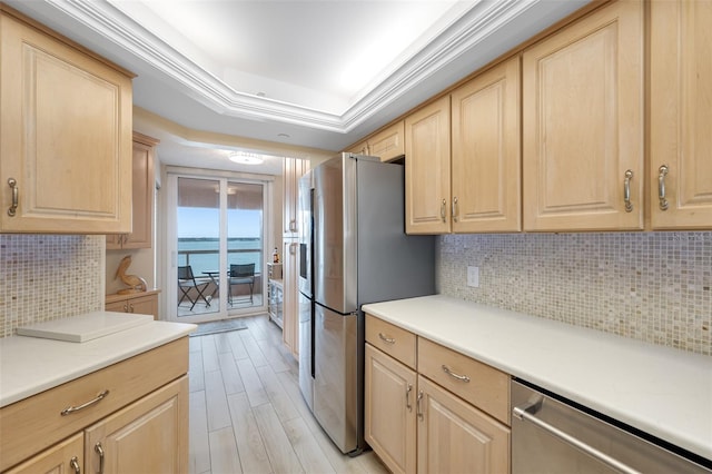 kitchen featuring a raised ceiling, a water view, tasteful backsplash, light brown cabinetry, and appliances with stainless steel finishes