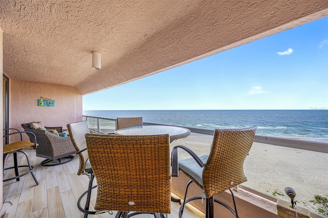 balcony featuring a water view and a beach view