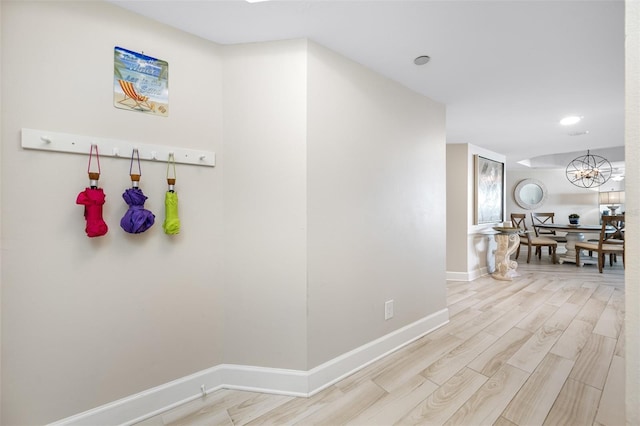 hallway with light hardwood / wood-style flooring and a chandelier