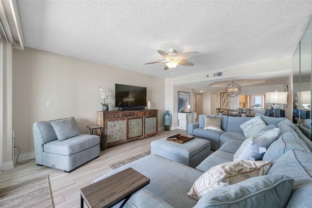 living room featuring a textured ceiling, light hardwood / wood-style floors, and ceiling fan with notable chandelier