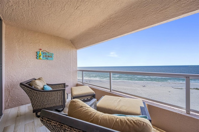 balcony with a water view and a view of the beach