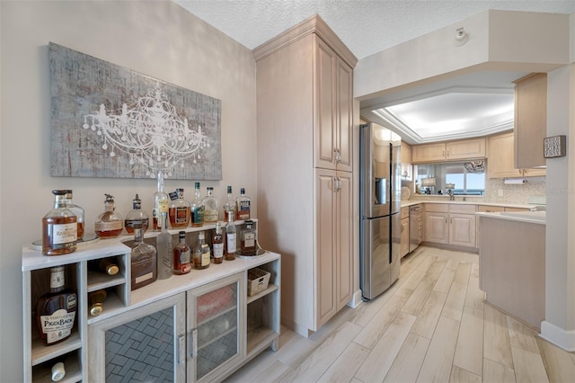 kitchen with sink, stainless steel appliances, light hardwood / wood-style flooring, a textured ceiling, and light brown cabinetry