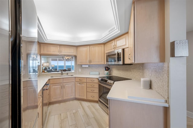 kitchen with light brown cabinets, sink, stainless steel appliances, and a tray ceiling