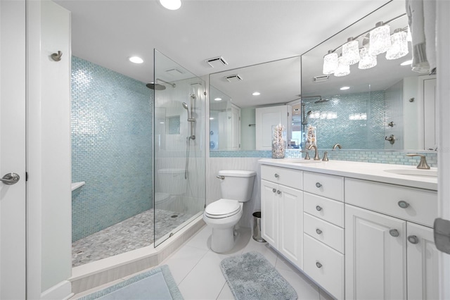 bathroom with tile patterned floors, vanity, toilet, and a tile shower