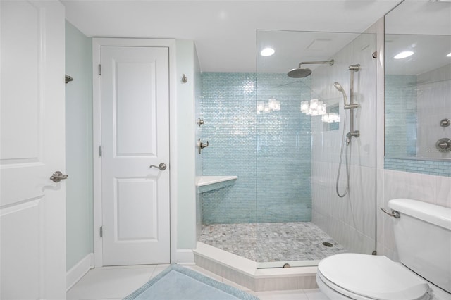 bathroom with tile patterned floors, toilet, and tiled shower