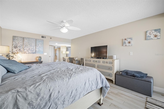 bedroom featuring light wood-type flooring, a textured ceiling, and ceiling fan