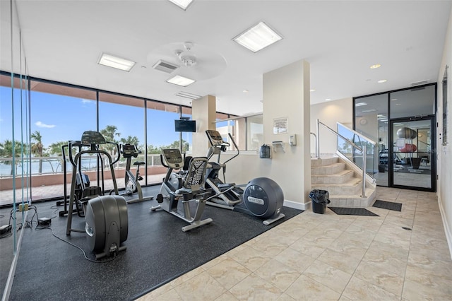 gym with ceiling fan, expansive windows, and a water view