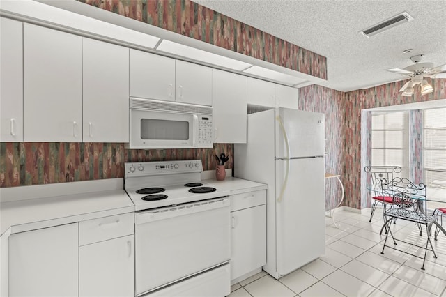 kitchen featuring a textured ceiling, white appliances, ceiling fan, light tile patterned floors, and white cabinetry