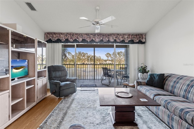 living room featuring hardwood / wood-style flooring, ceiling fan, and a textured ceiling