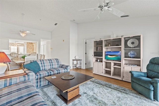 living room with hardwood / wood-style floors, a textured ceiling, vaulted ceiling, and ceiling fan