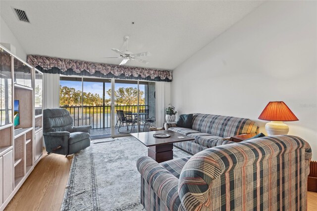 living room with ceiling fan, a water view, and light hardwood / wood-style floors