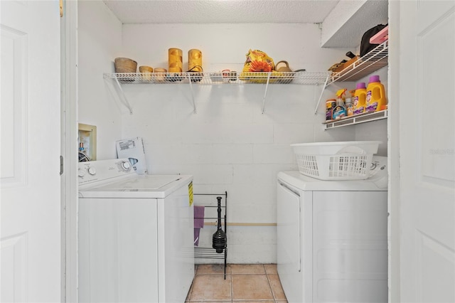 laundry area featuring light tile patterned flooring, a textured ceiling, and washing machine and clothes dryer