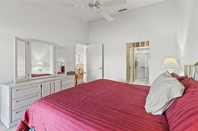 bedroom featuring ceiling fan, ensuite bathroom, and a high ceiling