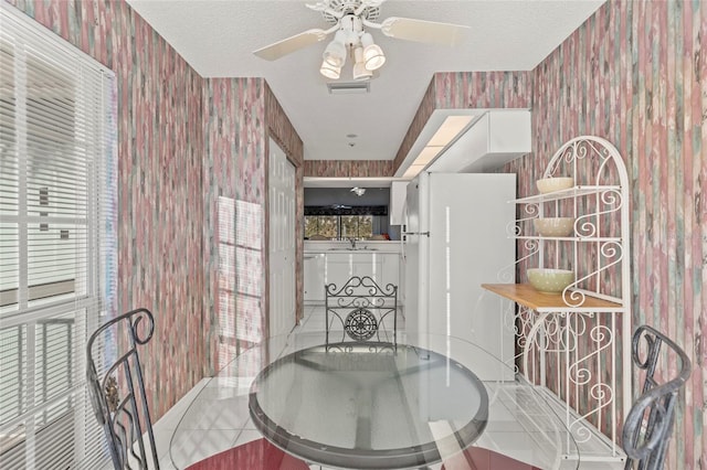 dining area with tile patterned flooring, a textured ceiling, ceiling fan, and sink