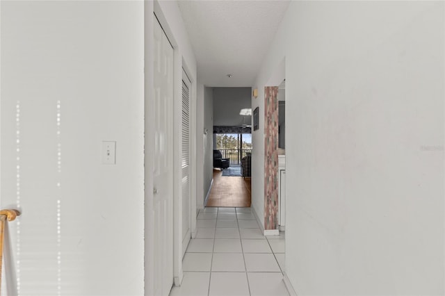 hallway featuring light tile patterned floors and a textured ceiling