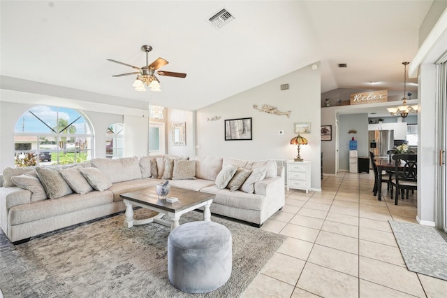 living room featuring ceiling fan with notable chandelier, light tile patterned floors, and vaulted ceiling