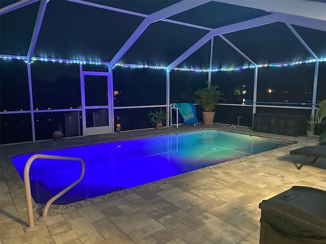 pool at twilight with a lanai and a patio area