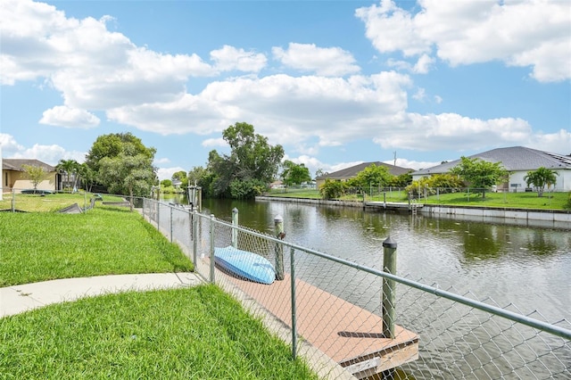 view of dock with a lawn and a water view