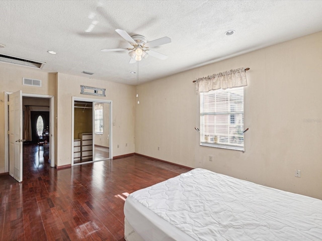 bedroom with ceiling fan, dark hardwood / wood-style floors, a textured ceiling, and a closet