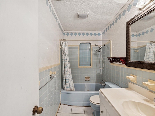 full bathroom featuring vanity, tile patterned flooring, toilet, a textured ceiling, and tile walls