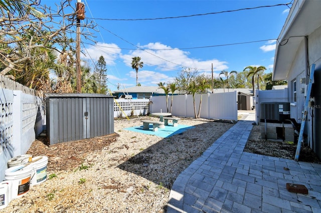 view of yard with central AC unit, a storage unit, and a patio area