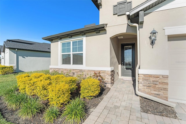 doorway to property with stone siding and stucco siding