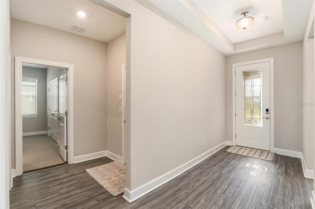 foyer featuring dark wood-style floors, baseboards, visible vents, and a raised ceiling