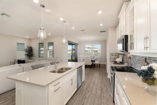 kitchen with visible vents, a sink, stainless steel appliances, white cabinetry, and backsplash