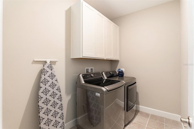 laundry area with cabinet space, light tile patterned floors, baseboards, and washer and clothes dryer